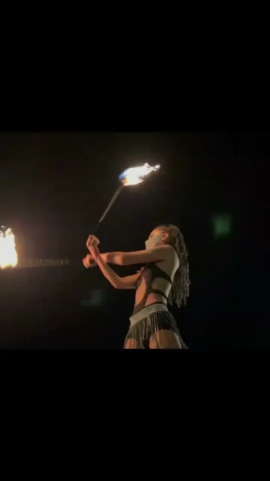 Play clip: a fire performer spinning a torch in the dark.